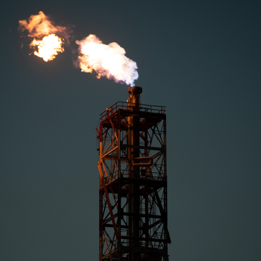 A gas flare stack burning off excess natural gas at night, symbolizing Oman's role in global natural gas exports