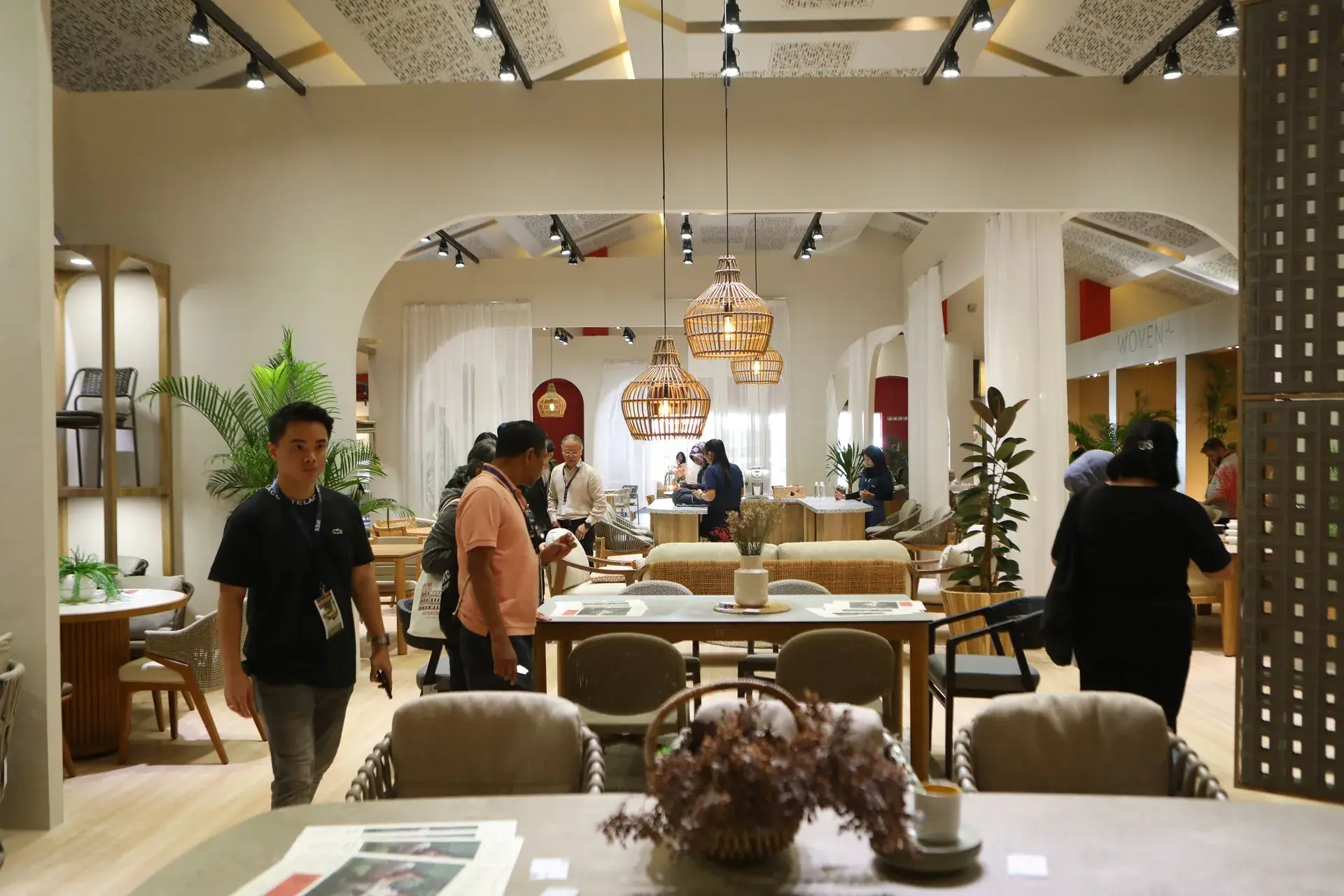 An image showing visitors browsing Indonesian wooden and rattan furniture displays at IFEX 2026